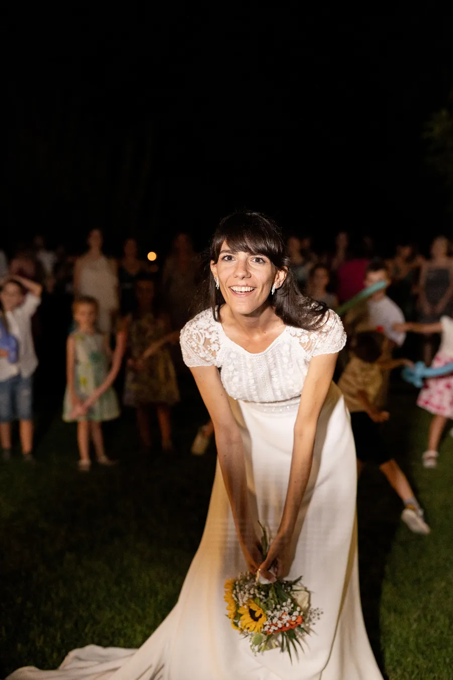 Bride bouquet toss at night celebration