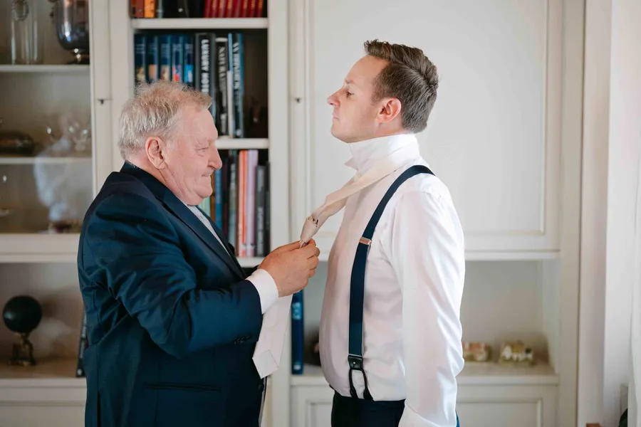 Father helping groom with his tie before the ceremony